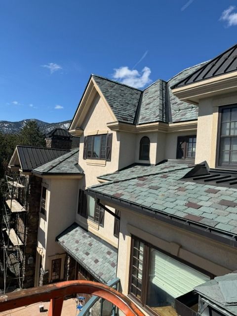 Apartment roofs and balconies with gray shingles under a bright blue sky