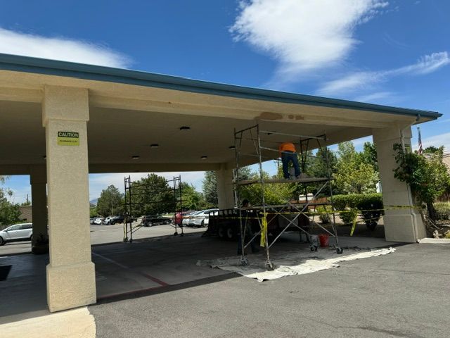 Covered outdoor parking area with construction scaffolding underneath on a sunny day
