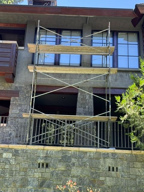 Building facade with scaffolding over a balcony and stone exterior wall