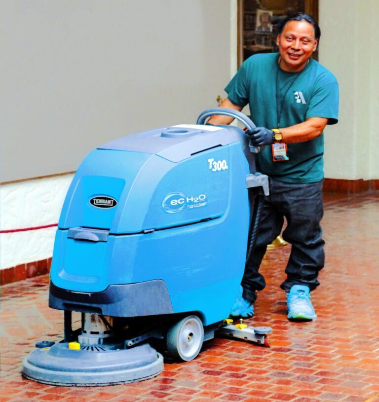 Man using a blue floor scrubber on a tiled floor indoors