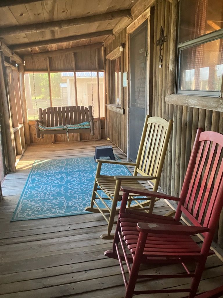 There are two rocking chairs on the porch of a house.