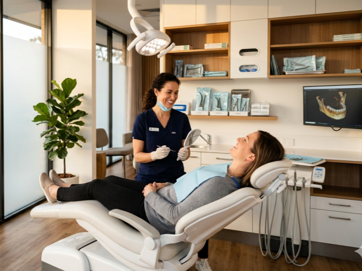 Dentist wearing a mask talks to a patient reclining in a modern dental clinic