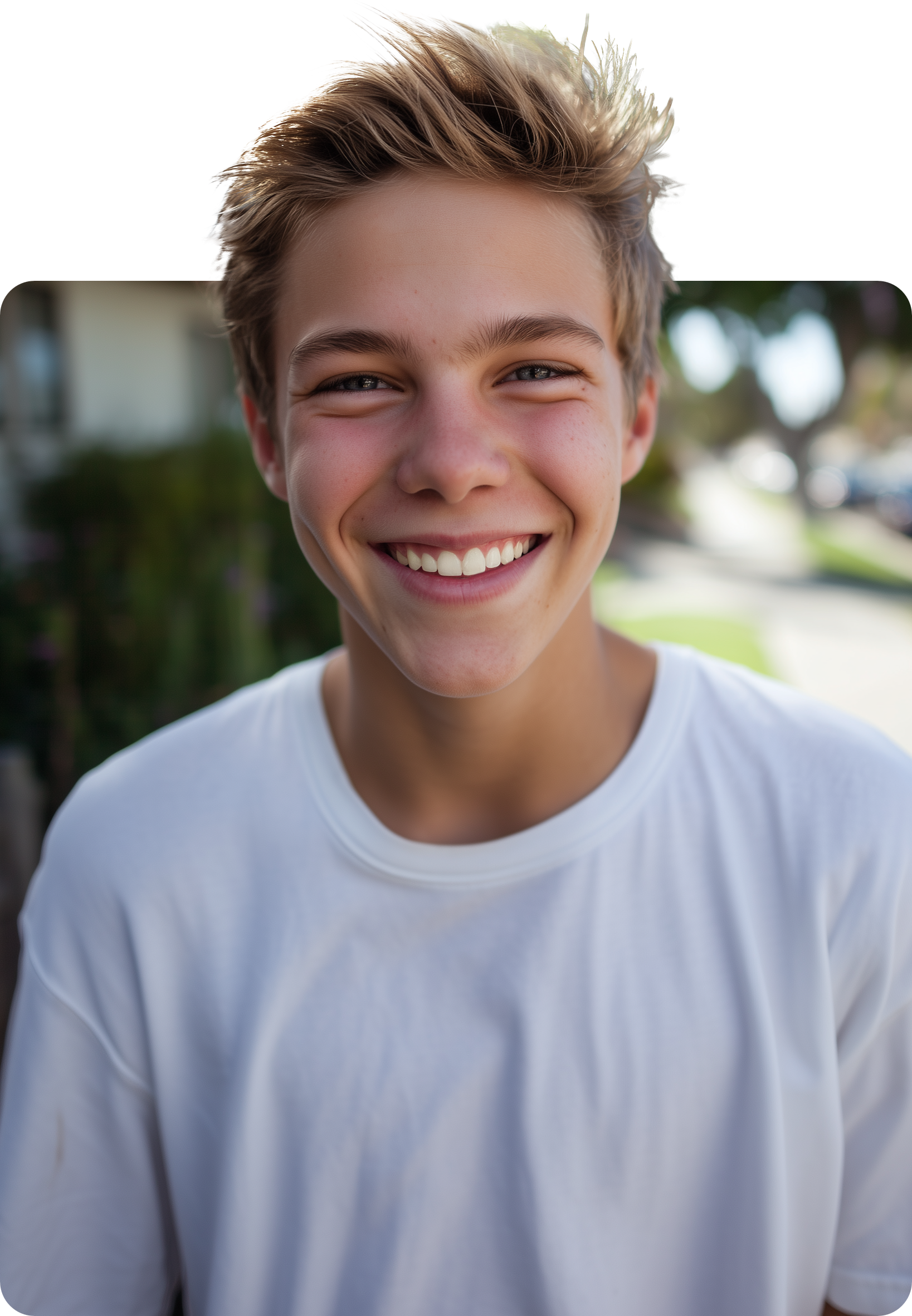 A young person with light brown hair and a bright, friendly smile, wearing a white shirt in an outdoor setting.