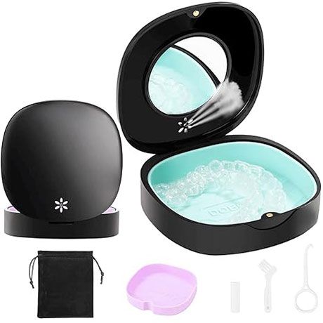 Black oval tabletop humidifier with open lid, aqua water basin, and accessories laid out beside it