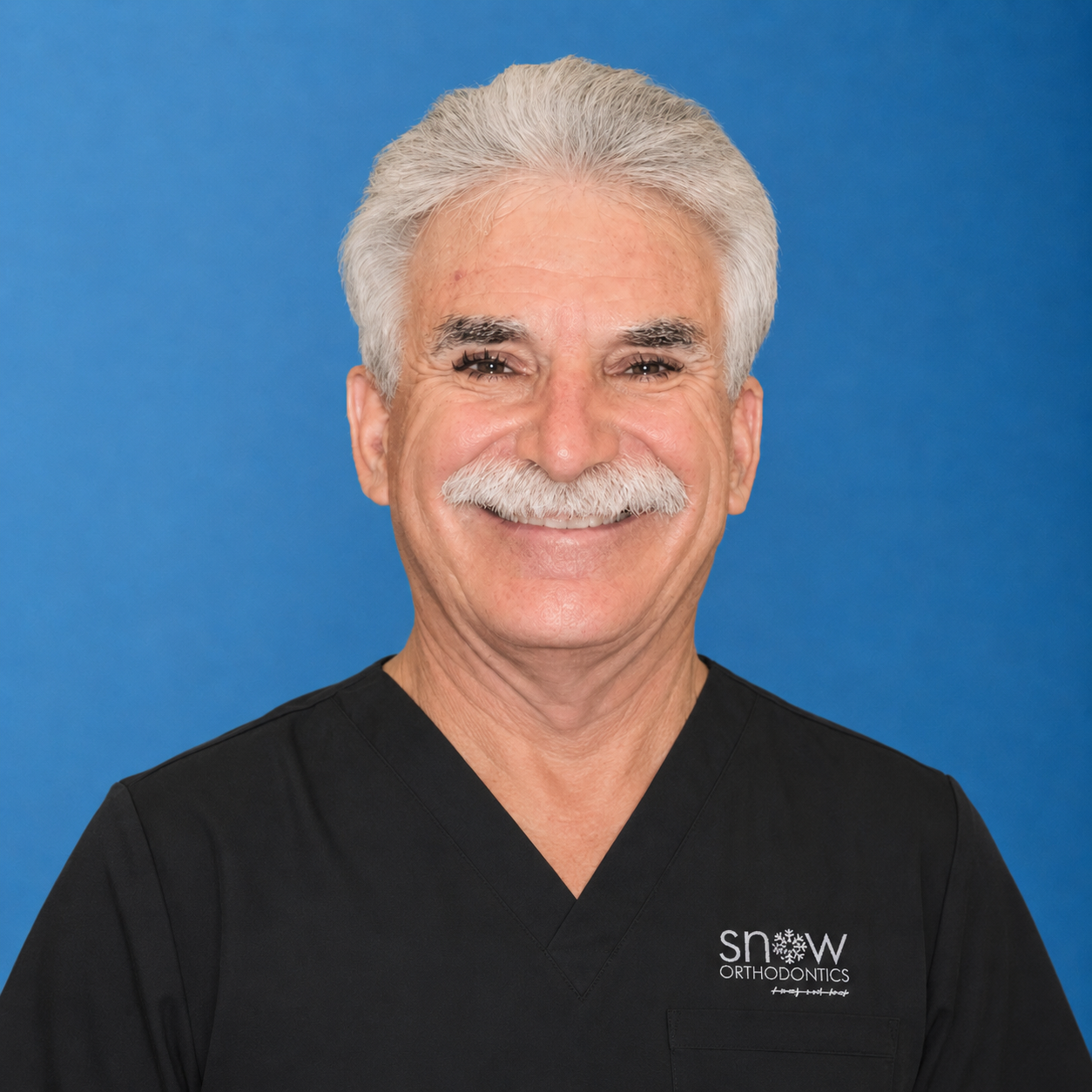 Smiling man in black scrubs against a blue background