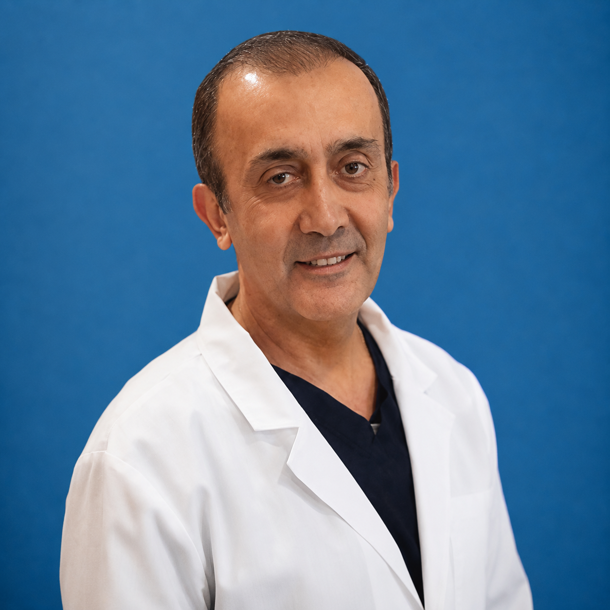 Man in a white lab coat smiling against a blue background