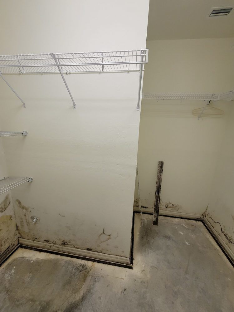 A closet with a metal rack on the wall and a concrete floor.