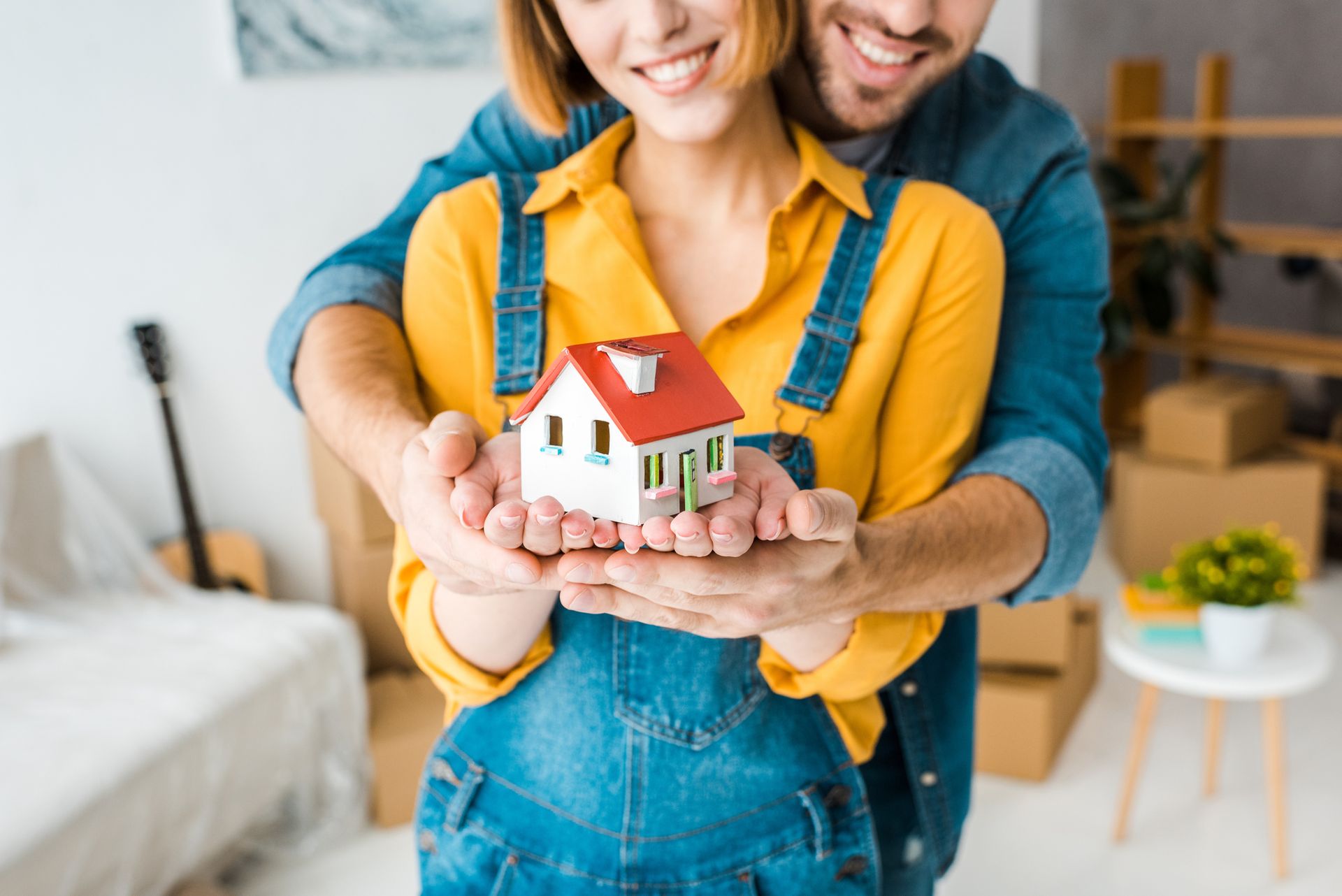 A man and a woman are holding a model house in their hands.