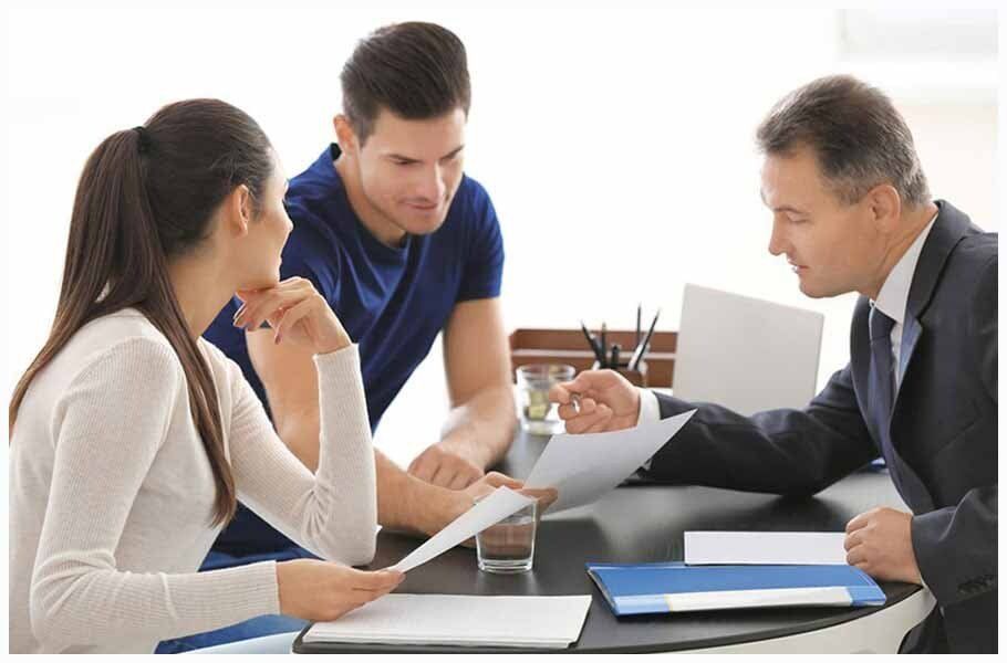 A man and a woman are sitting at a table talking to a lawyer.