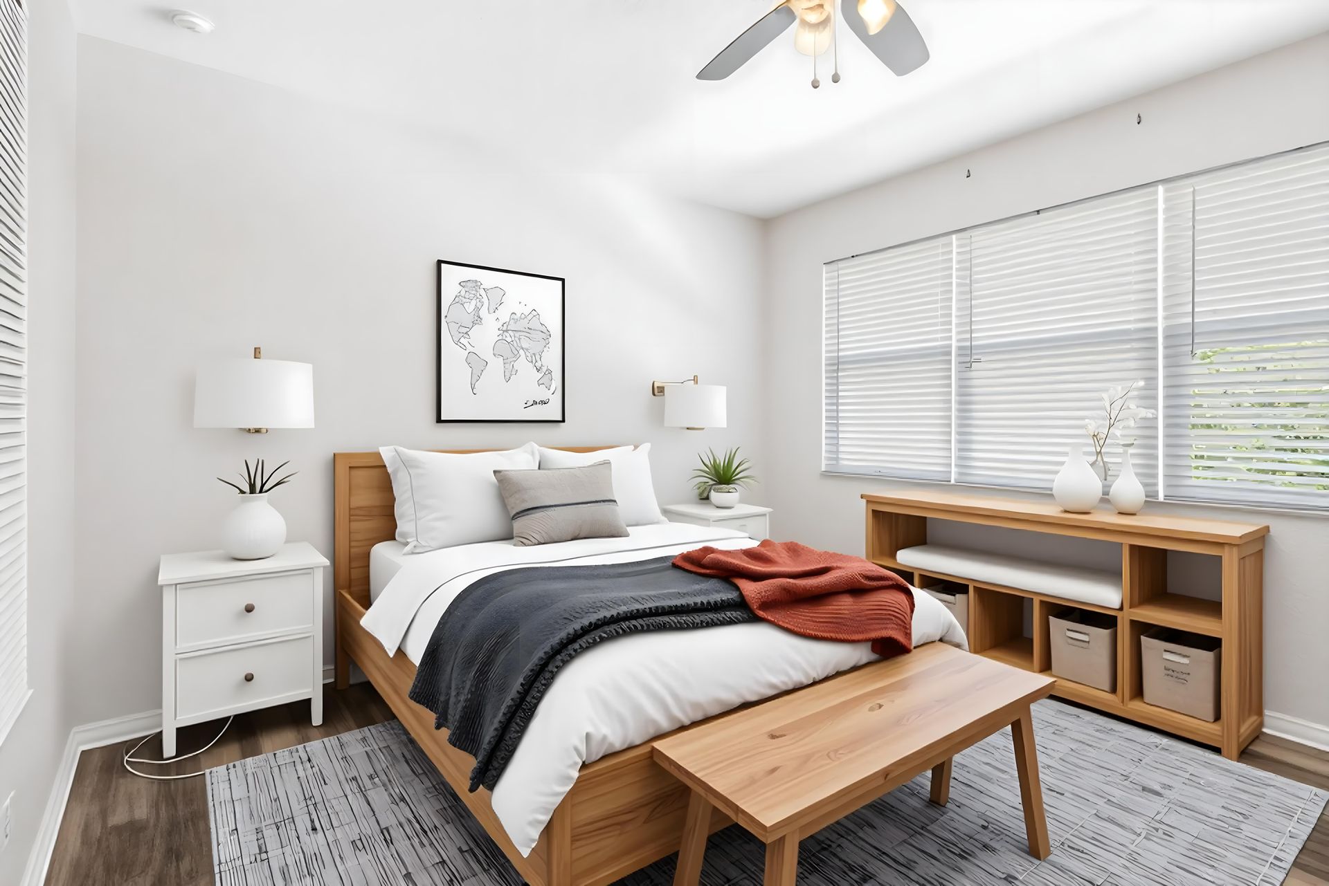 A modern, bright bedroom with a wood bed frame, white bedding, nightstands, and a long wooden storage bench near a window.