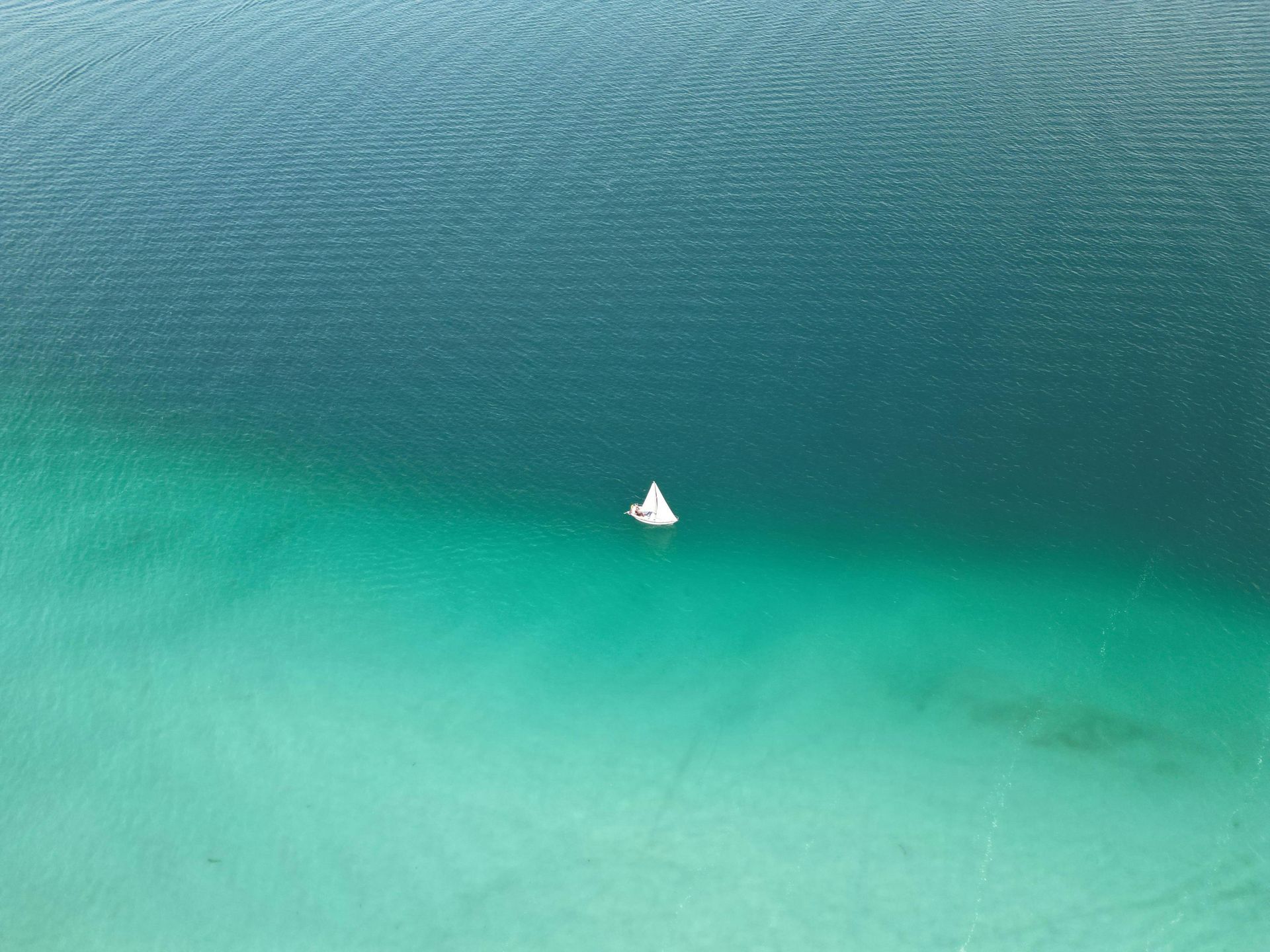 Sailboat on turquoise and blue water.