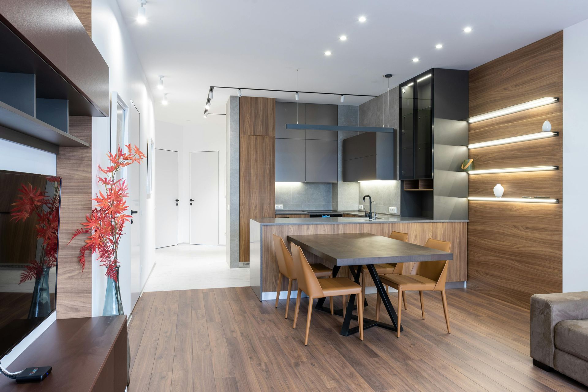 Modern kitchen and dining area with wood cabinets, gray countertops, and brown leather chairs.