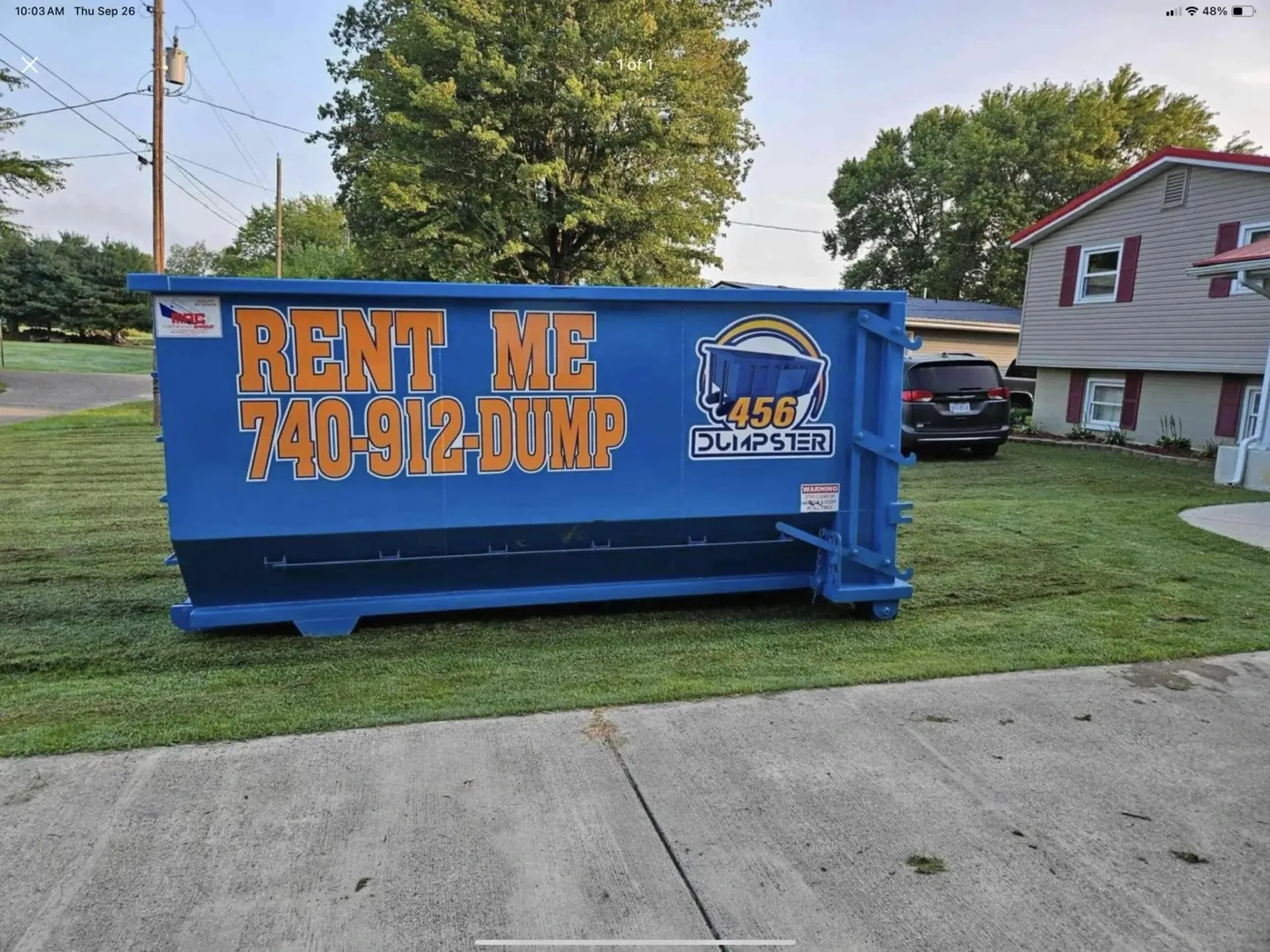 A row of dumpsters are parked in a gravel lot.