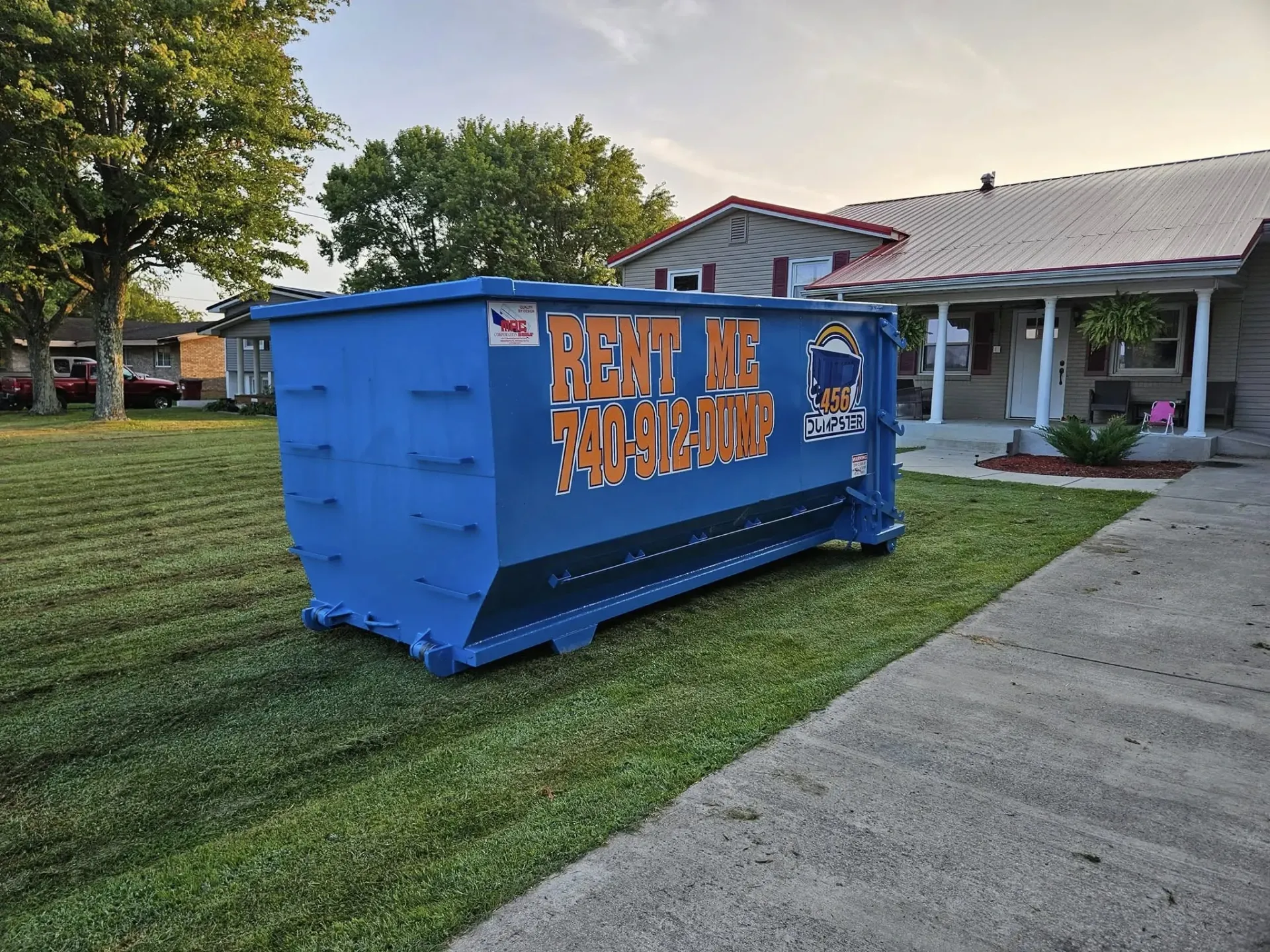 A dumpster is being pulled by a truck on a trailer.