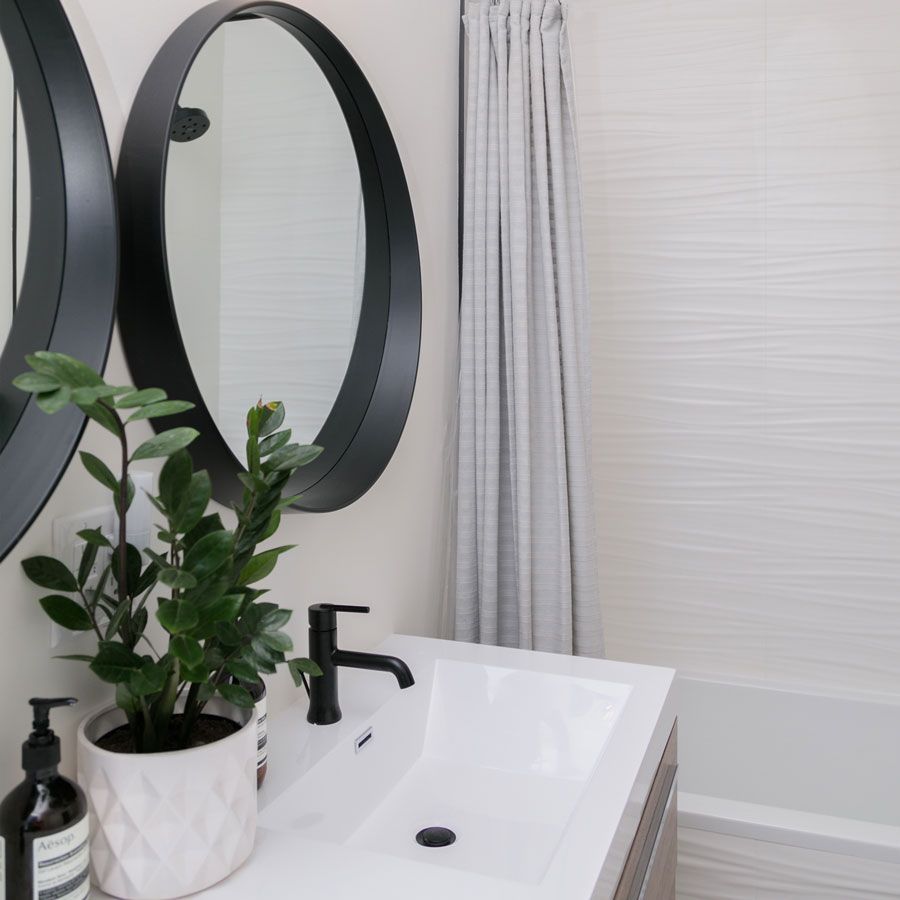 A bathroom with a sink and two mirrors