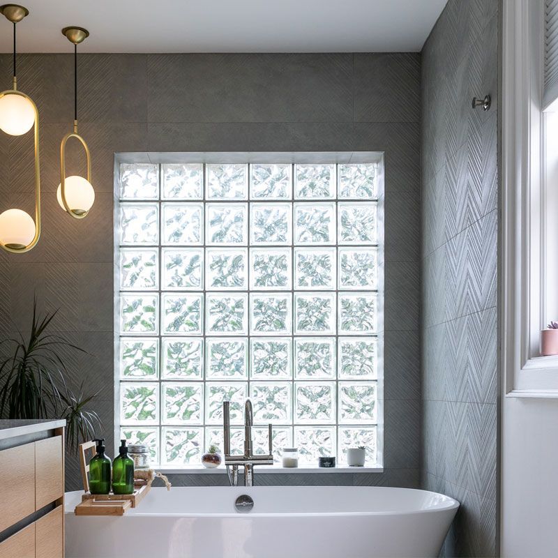 A bathroom with a tub and a window with glass blocks