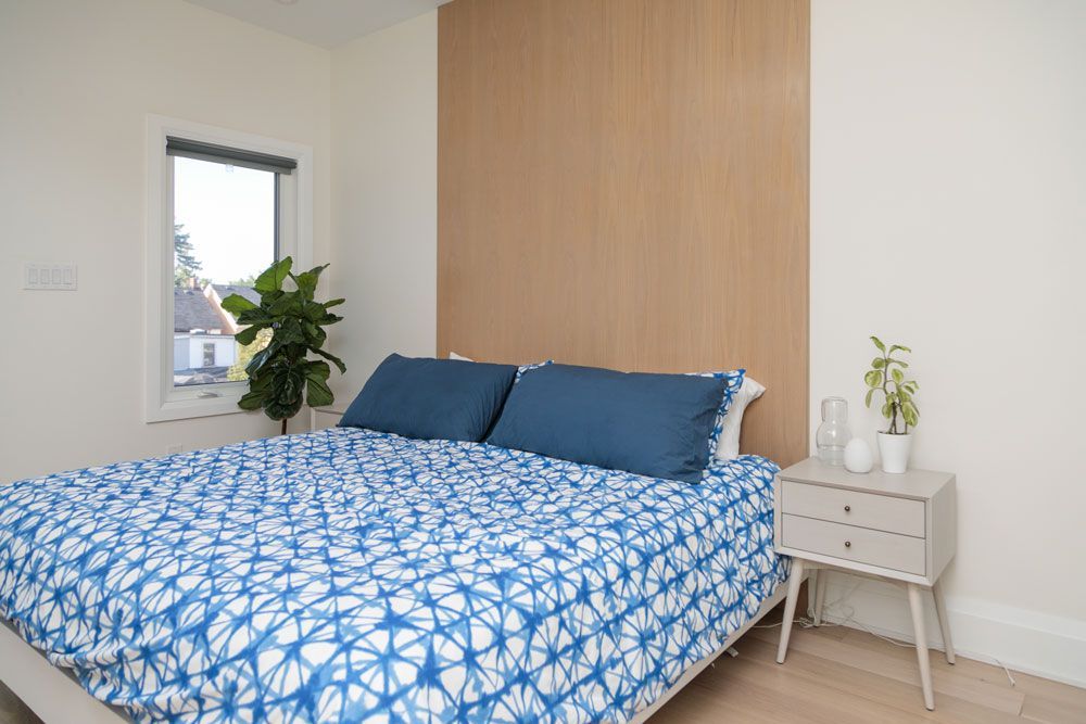 A third-story addition bedroom with a bed, nightstand, and window.