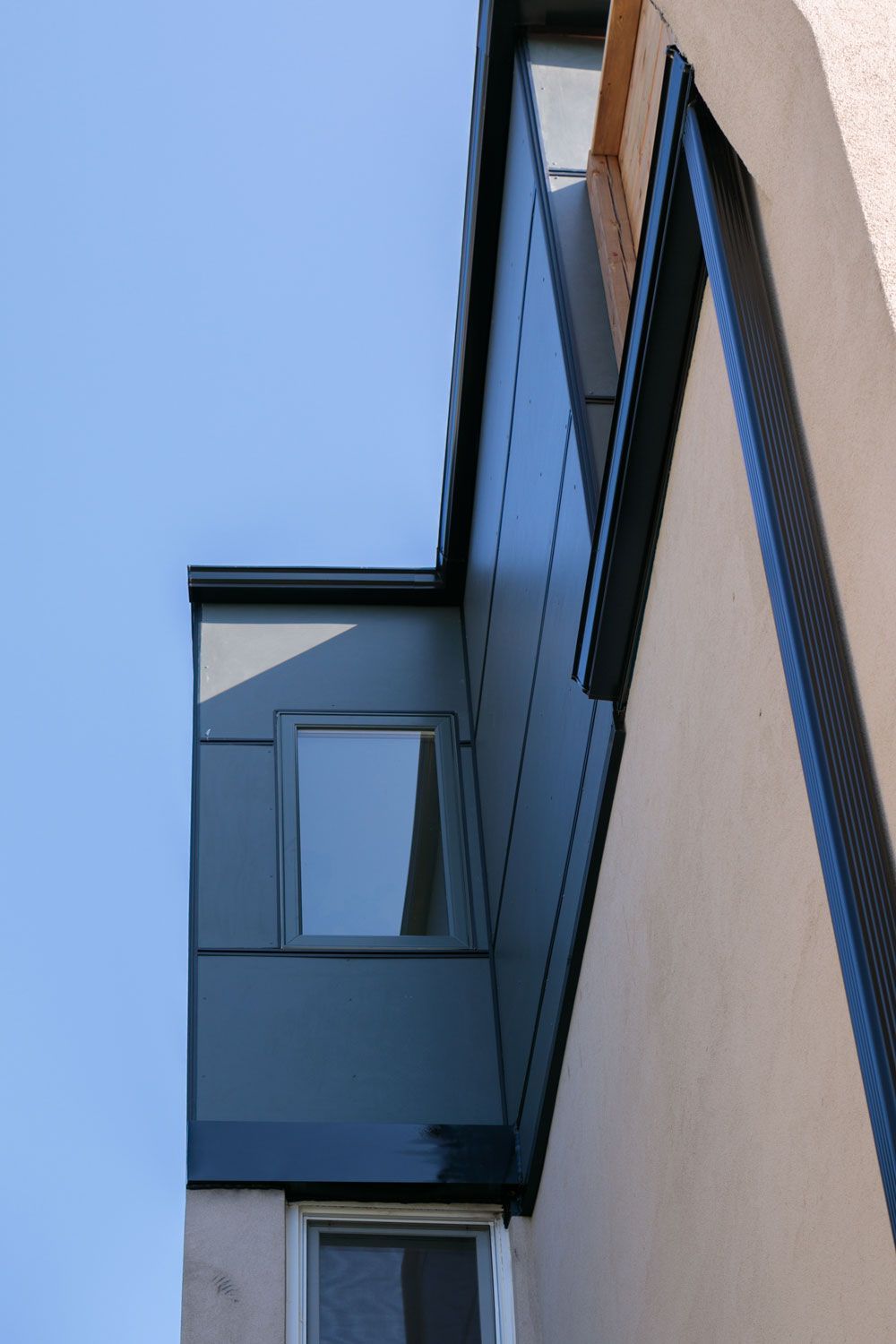 Looking up at a third story addition building with a blue sky in the background
