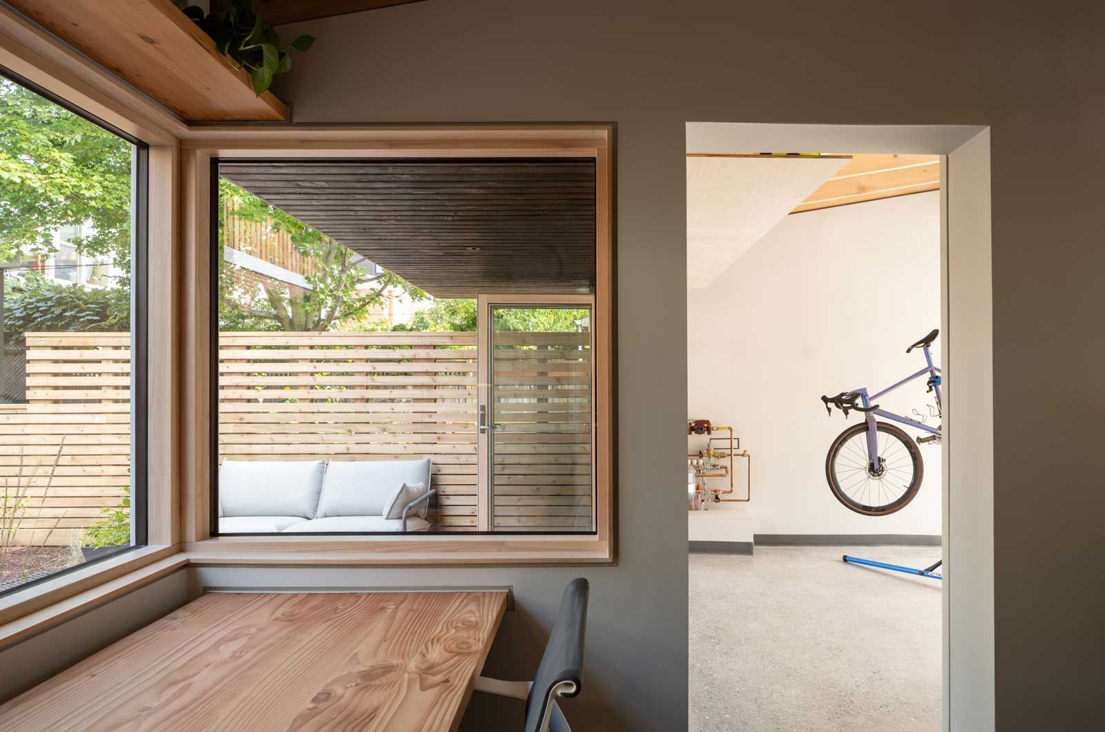 A bicycle is hanging on a wall in a room next to a window.