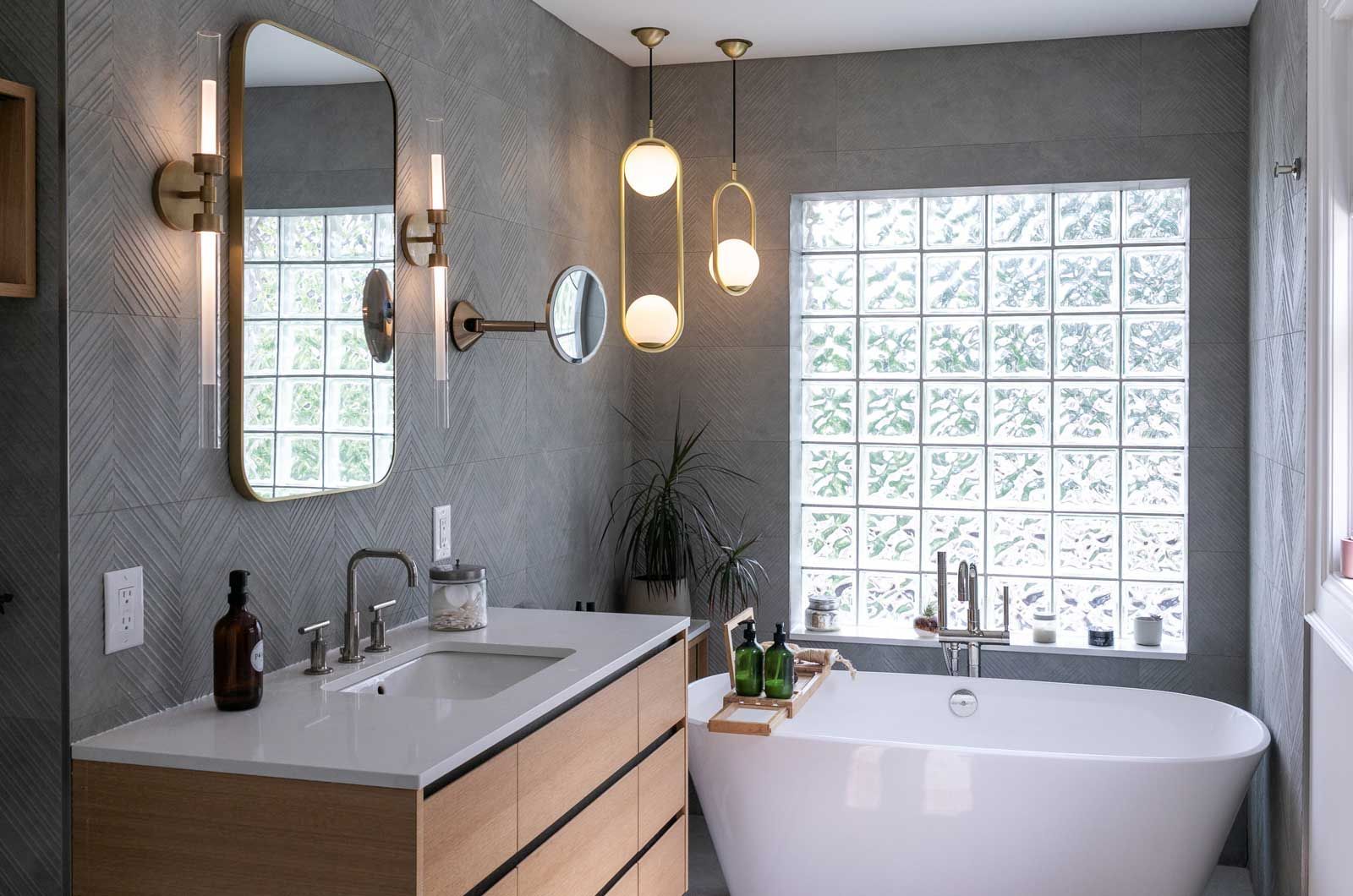A bathroom remodel with a tub, sink, mirror, and window.
