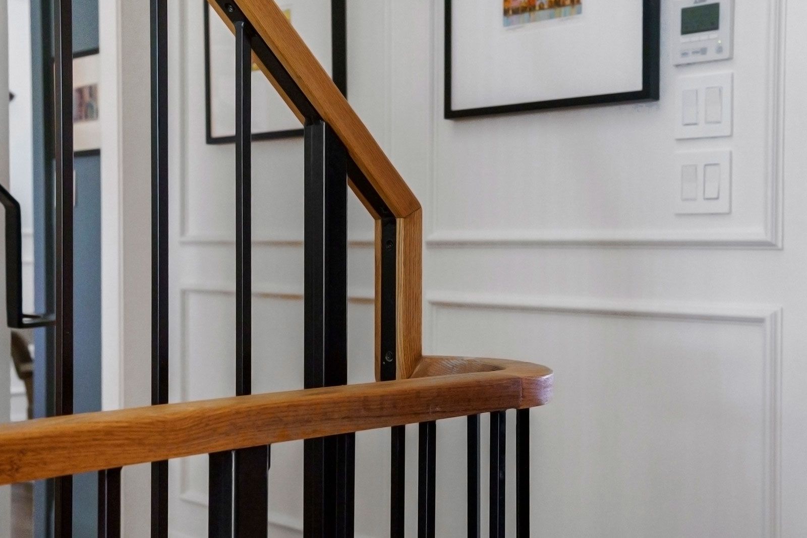 Modern staircase with wooden handrails and black metal balusters in a bright hallway