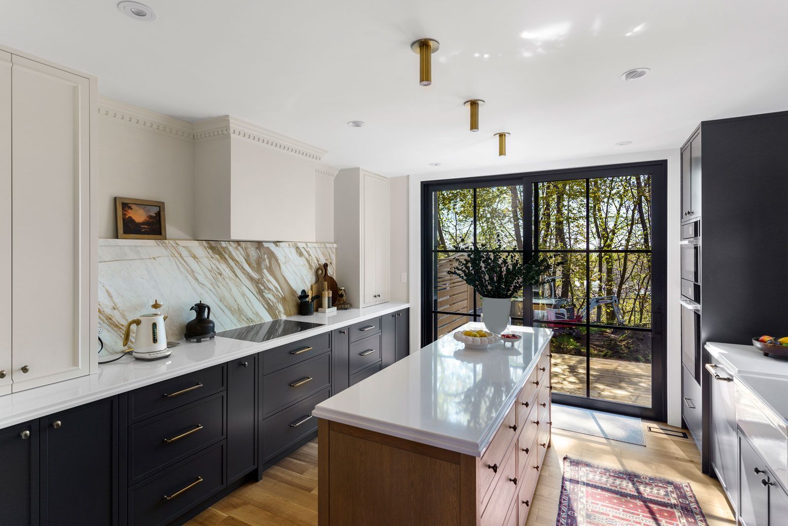 Bright modern kitchen with black-and-white cabinets, marble island, and sliding glass doors to a garden