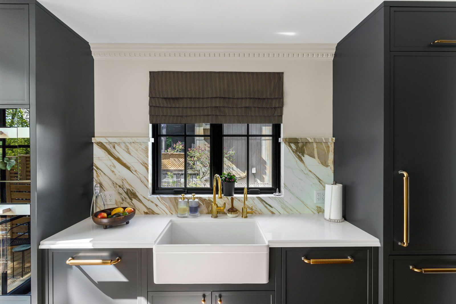Modern kitchen with dark cabinets, white farmhouse sink, and window with striped valance