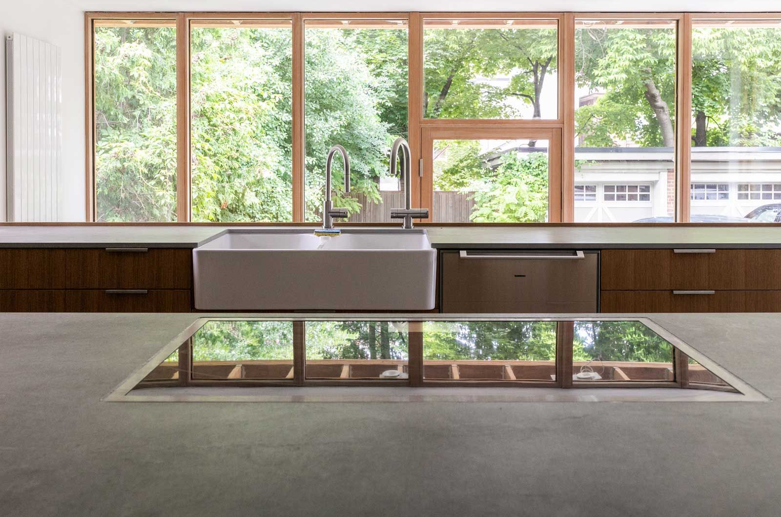A kitchen with a sink , stove top oven , and large windows.