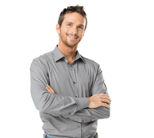 A man in a grey shirt is standing with his arms crossed and smiling.