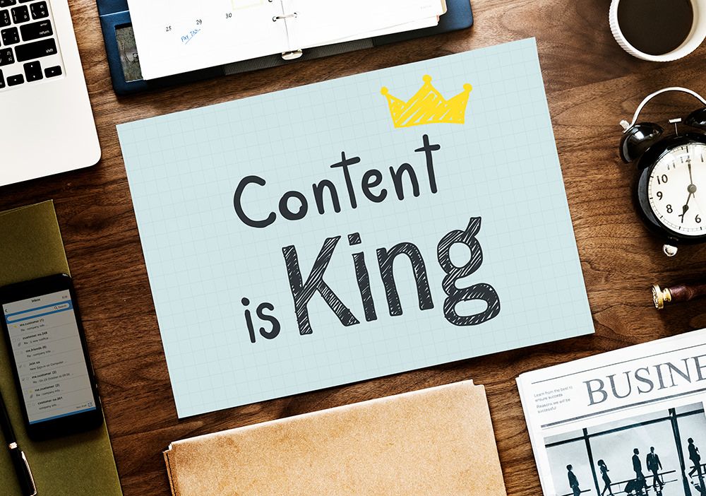 A wooden desk with a sign that says content is king