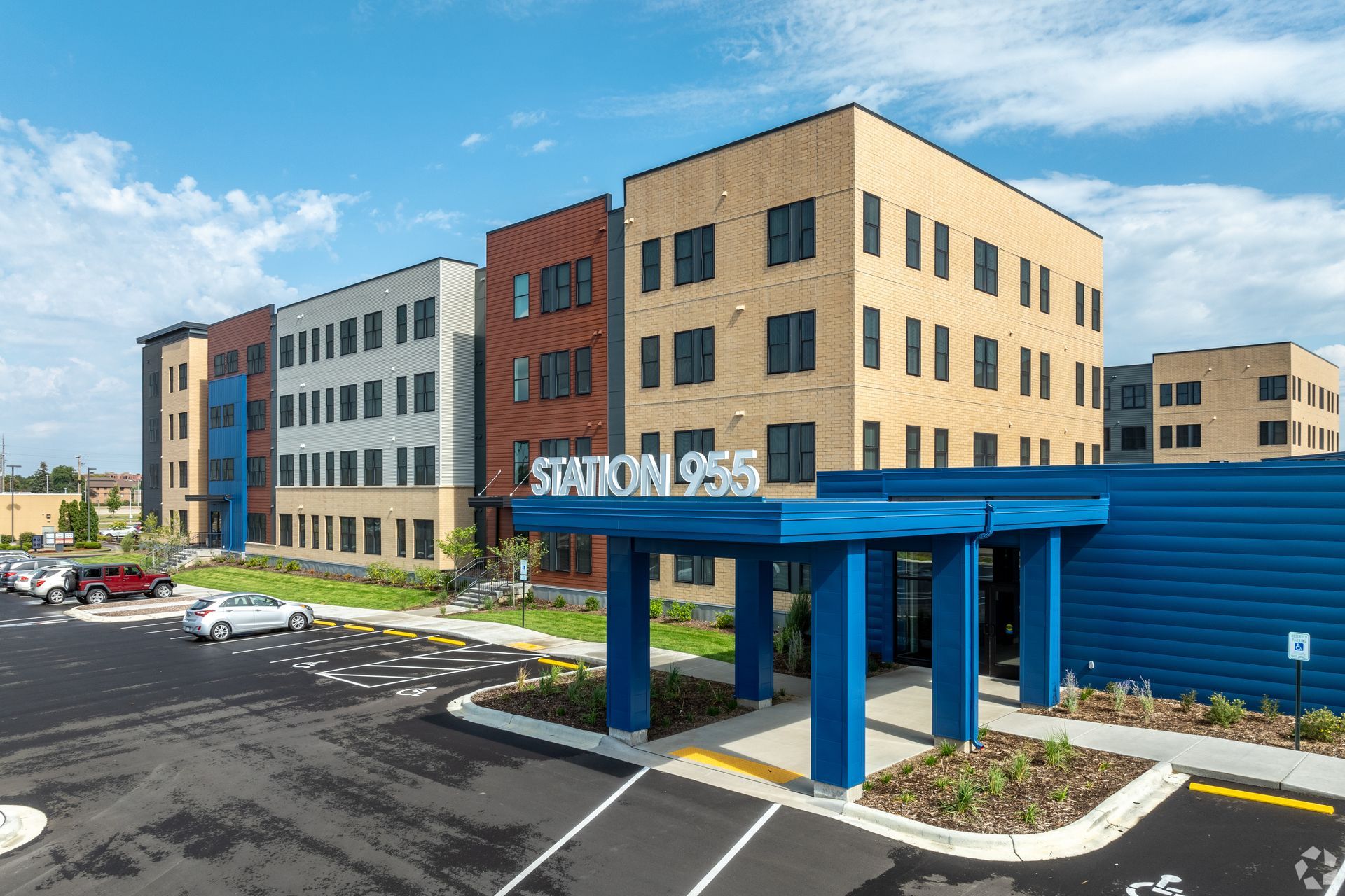 Exterior of a multifamily apartment building with blue, grey, and orange tones