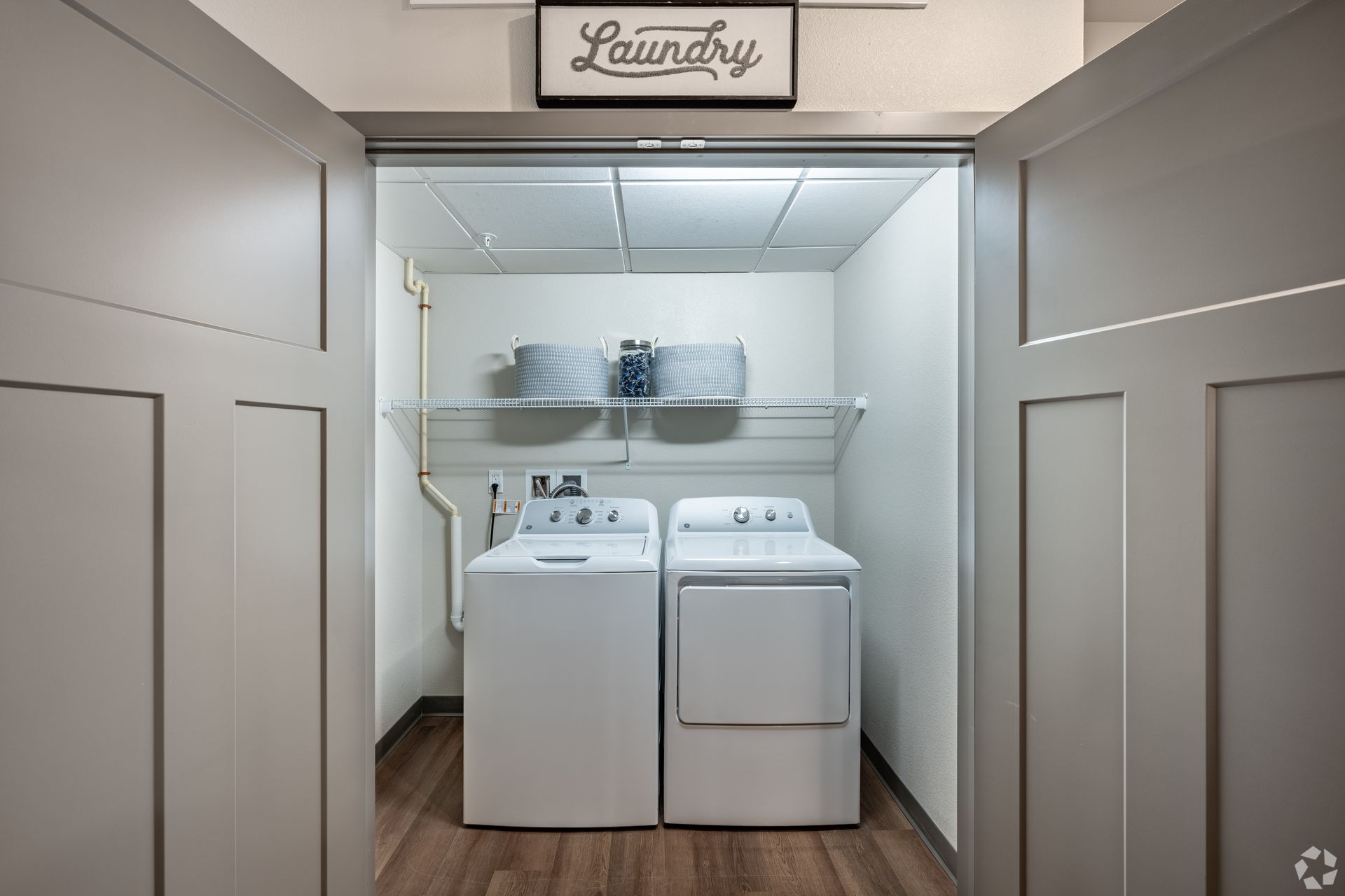 Laundry room with a washer and dryer inside of a closet with grey doors