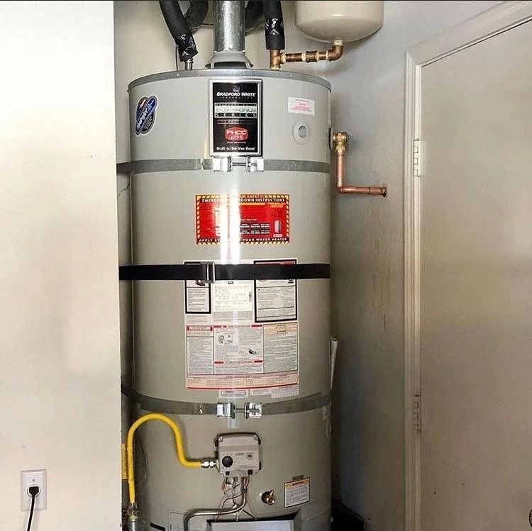 Large gray water heater with pipes and labels in a utility closet