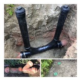 Black PVC pipes forming a Y-shaped drain line exposed in a dirt trench, with a small repair inset below