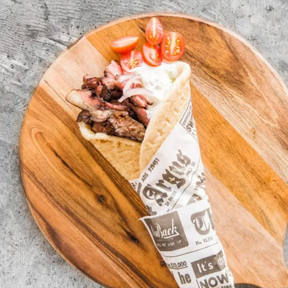A souvlaki wrap with meat and tomatoes on a wooden cutting board from Food Truck catering in Melbourne.