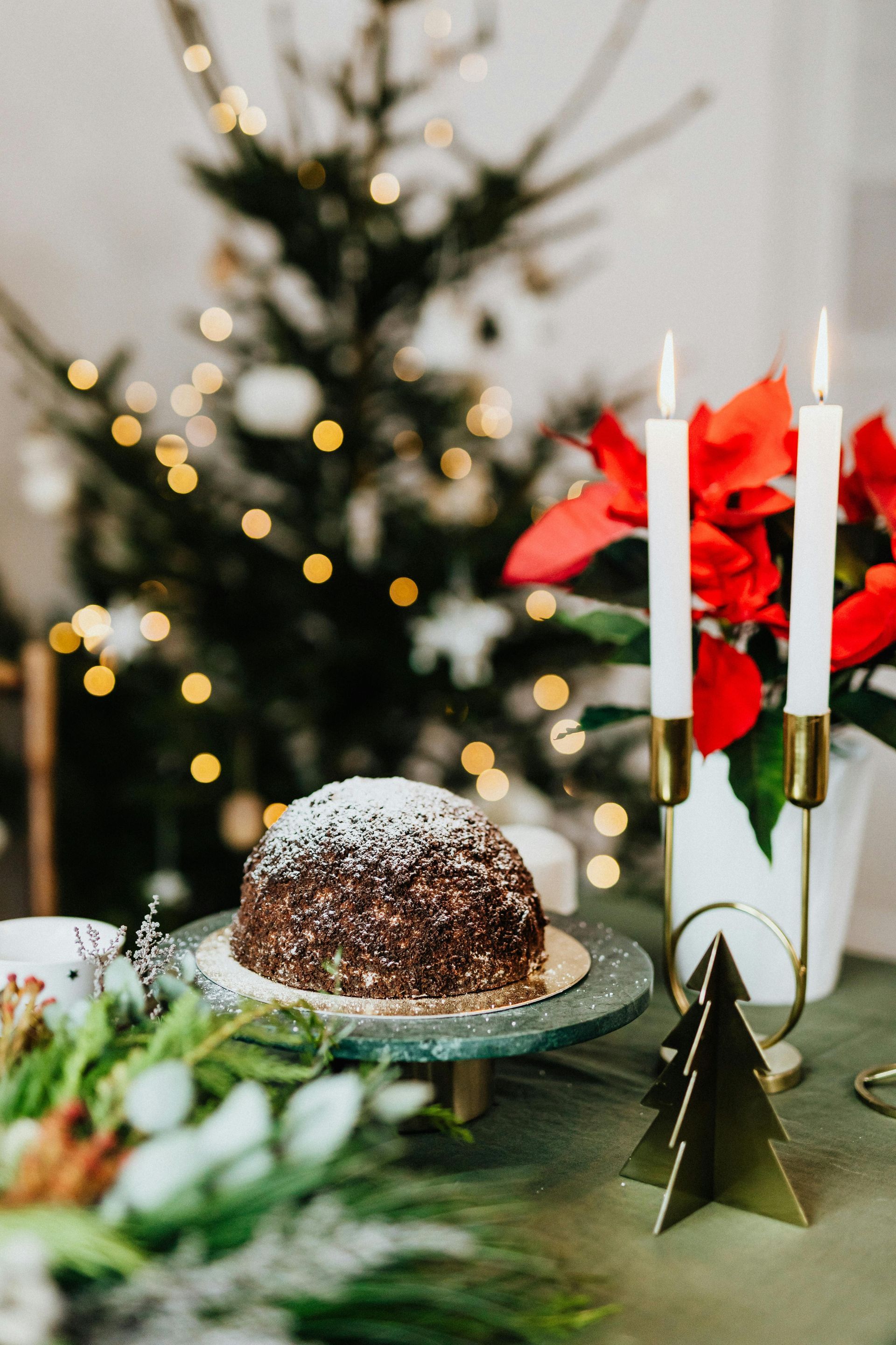 There is a christmas tree in the background and a cake on the table.