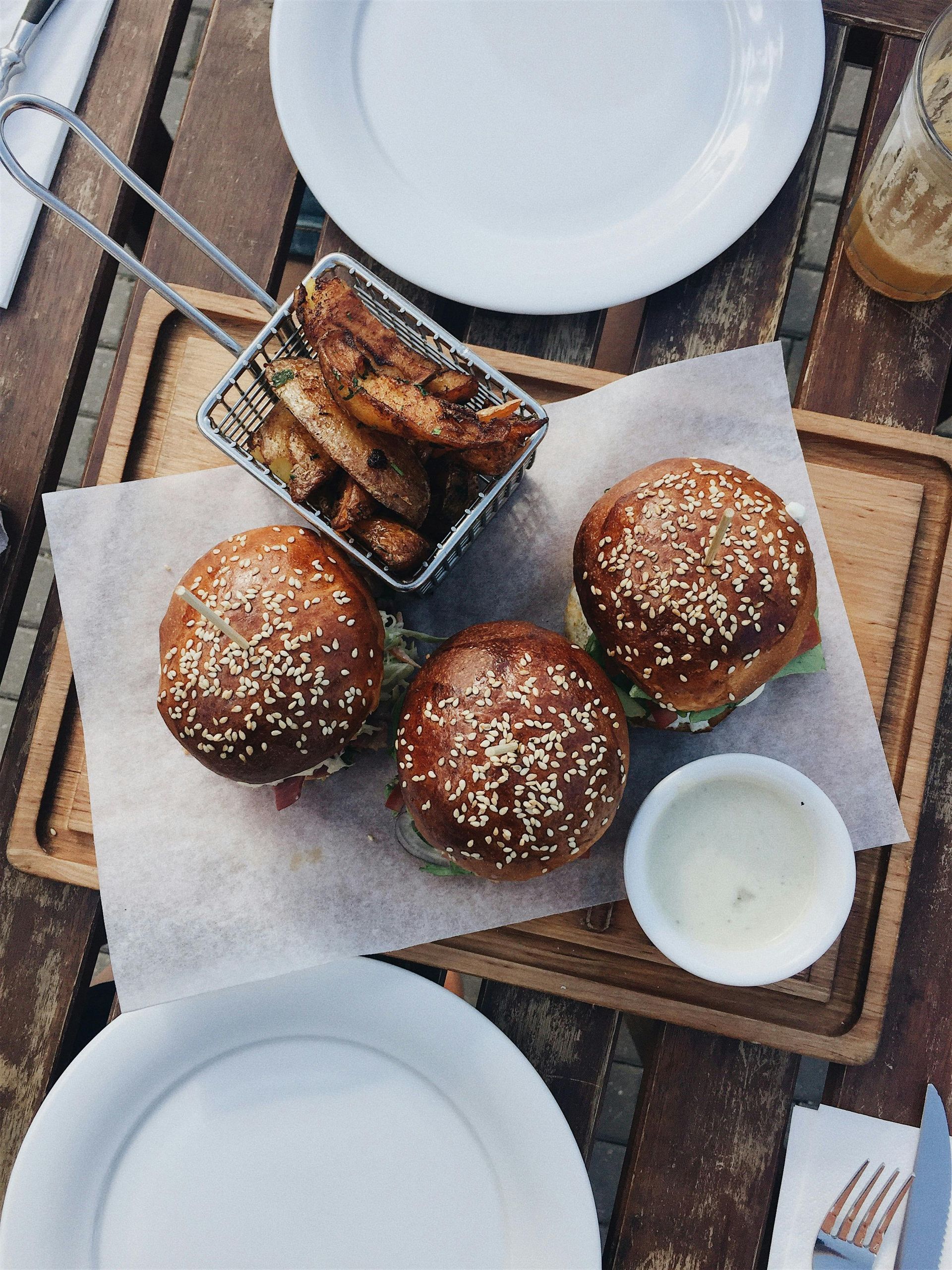 Three hamburger sliders and a basket of french fries on a wooden cutting board