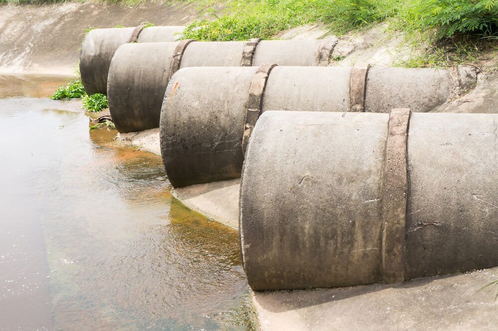 A Row Of Concrete Pipes Draining Water Into A River — Flash Concreting Pty Ltd In Nebo, QLD