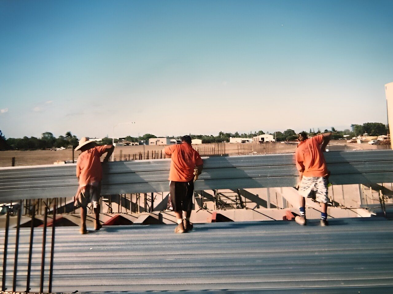 A Group Of Men Are Standing On A Metal Roof — Flash Concreting Pty Ltd In Nindaroo, QLD