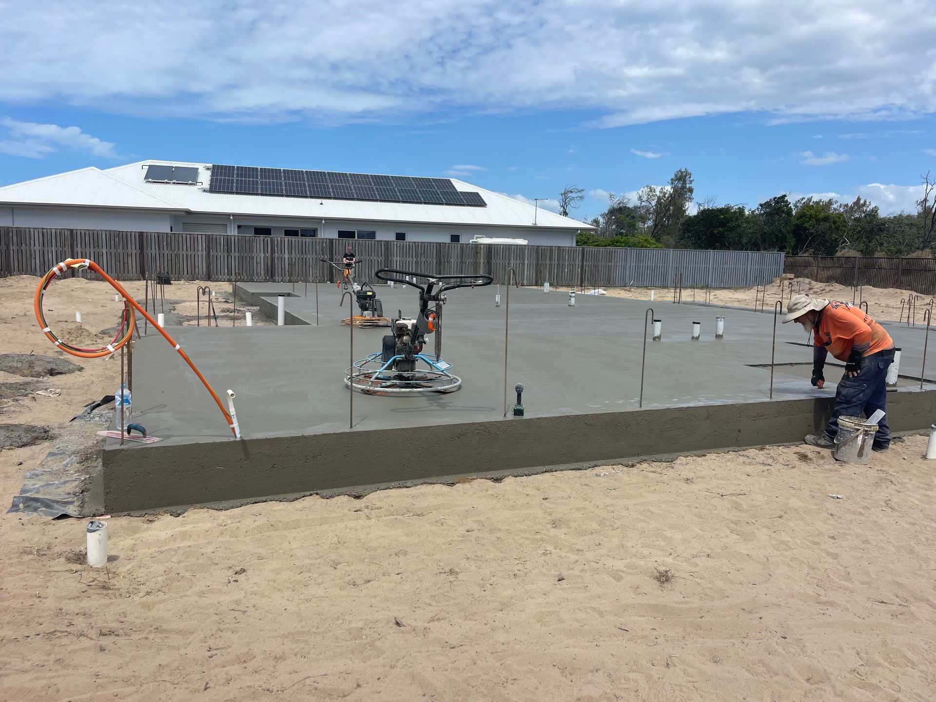 Workers smoothing fresh concrete at a construction site under a blue sky — Flash Concreting Pty Ltd In Nindaroo, QLD
