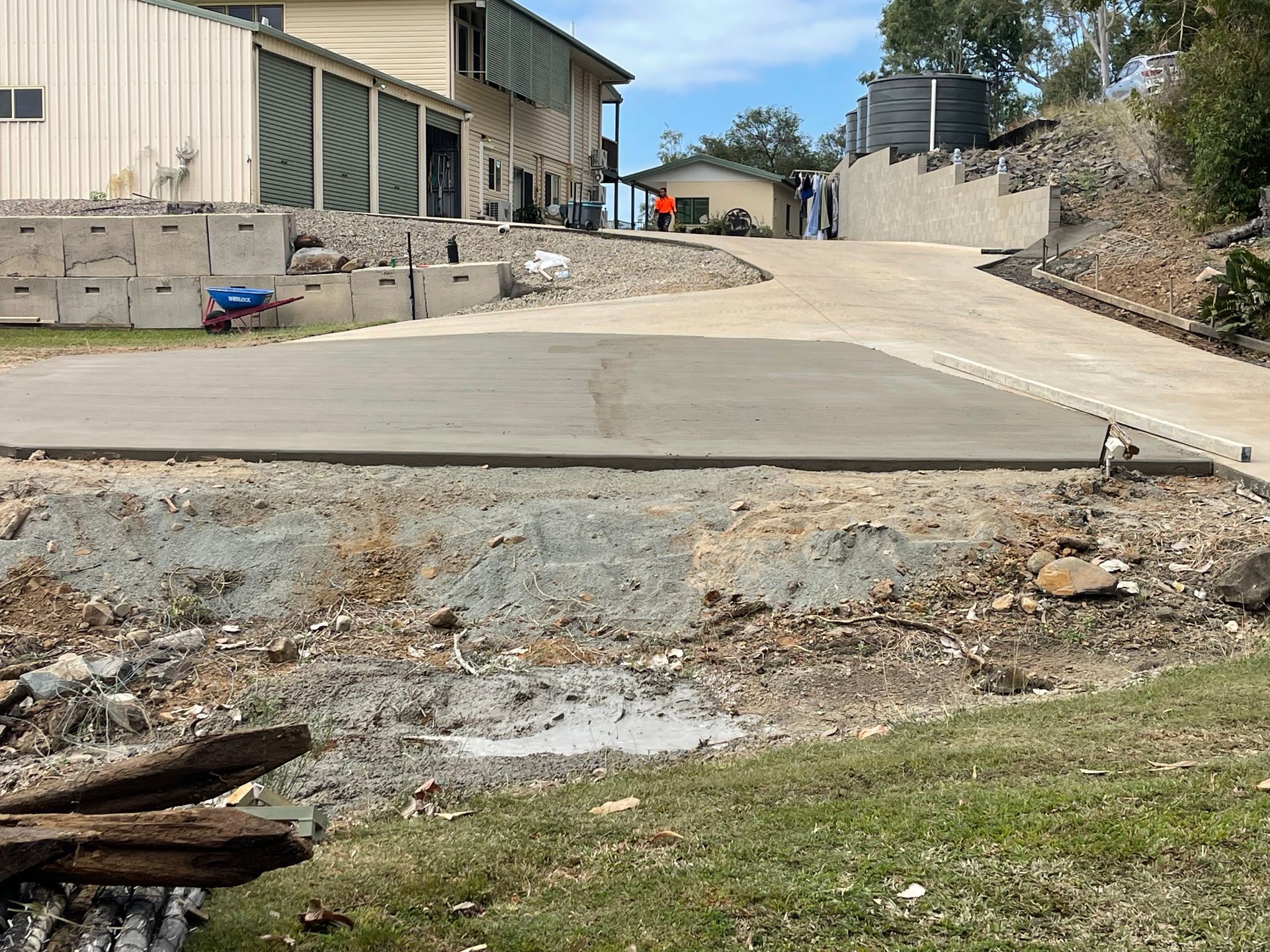 Concrete driveway on a sloped path between beige buildings under a blue sky — Flash Concreting Pty Ltd In Nindaroo, QLD