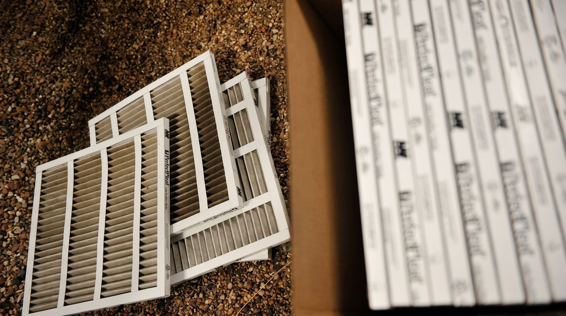Outdoor air conditioning unit beside a brick wall on a patio, with a protective top grille.