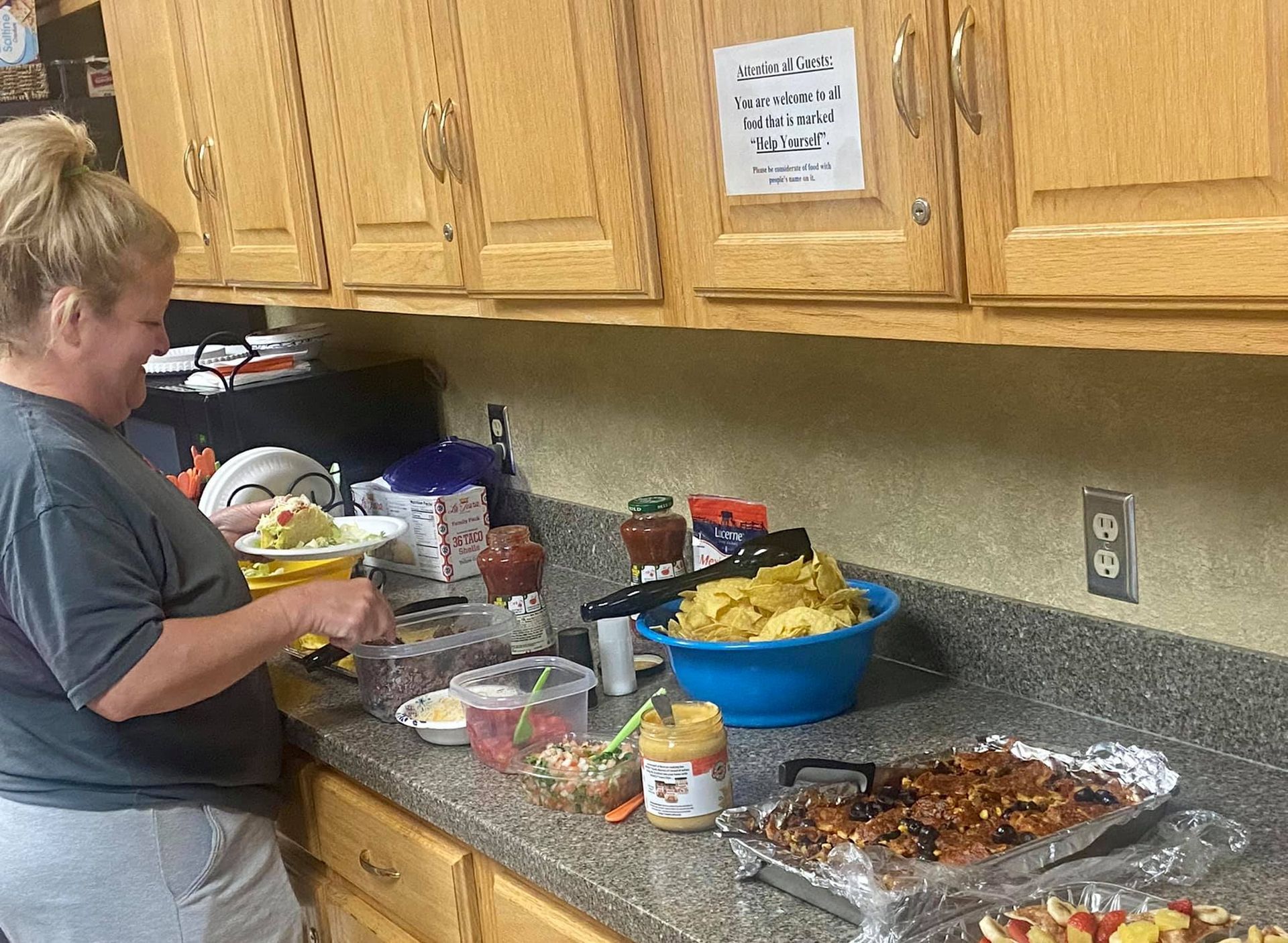 Woman preparing food on a countertop in a kitchen, with snacks and ingredients for a party.