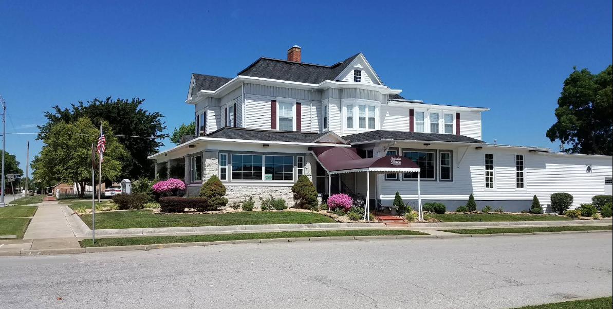 two-story white house with several windows, grey roof and awning over the front door.