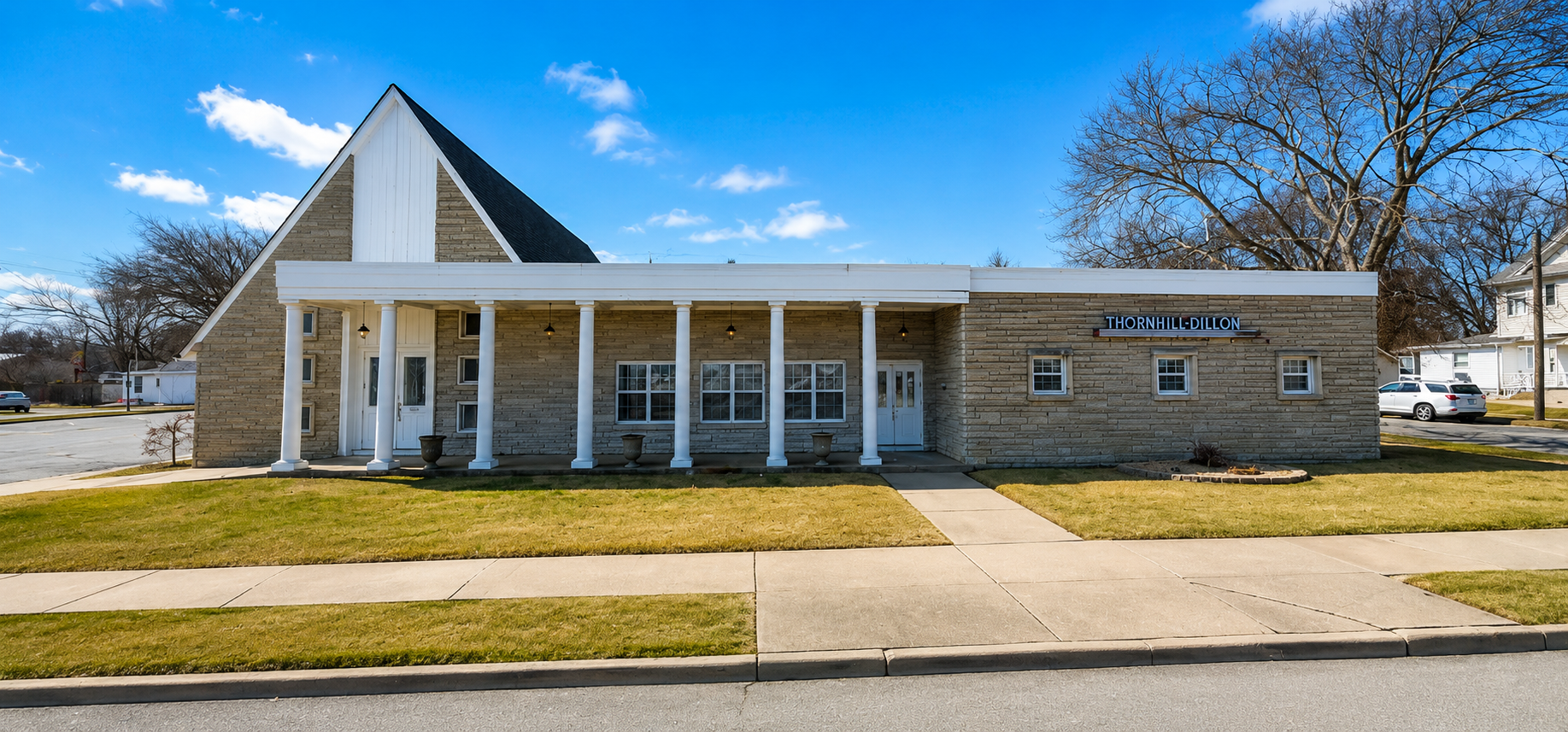 one-story, grey brick building with pointed roof on one side and a flat roof on the other.