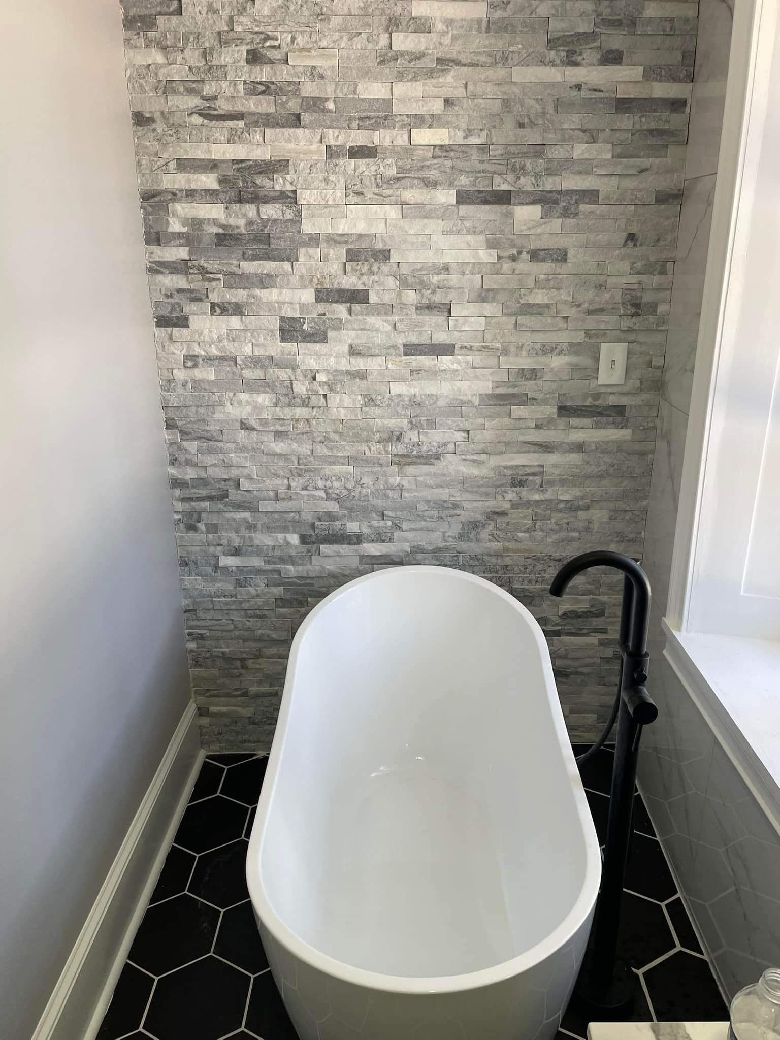 Aqua Plumbing Pros | A white bathtub is sitting in a bathroom next to a brick wall.