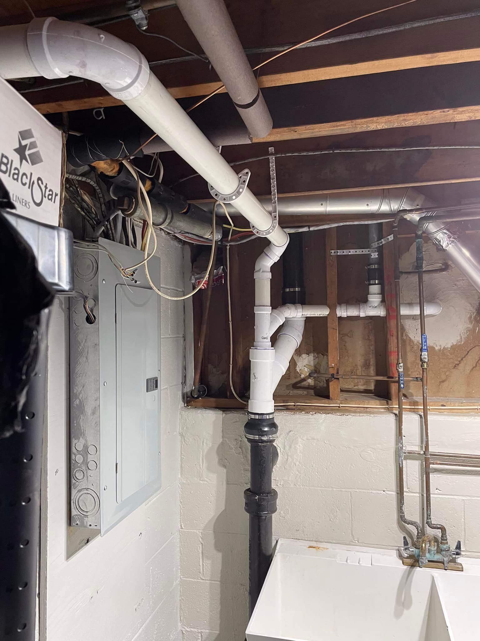 Aqua Plumbing Pros | A basement with a lot of pipes hanging from the ceiling.