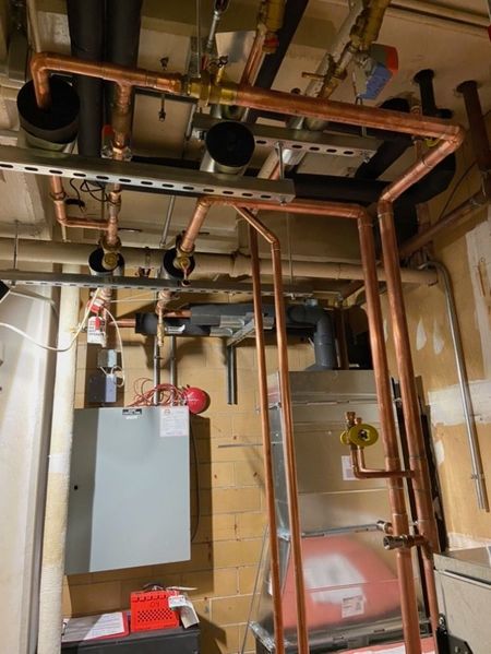 Aqua Plumbing Pros | A room with a lot of pipes hanging from the ceiling.