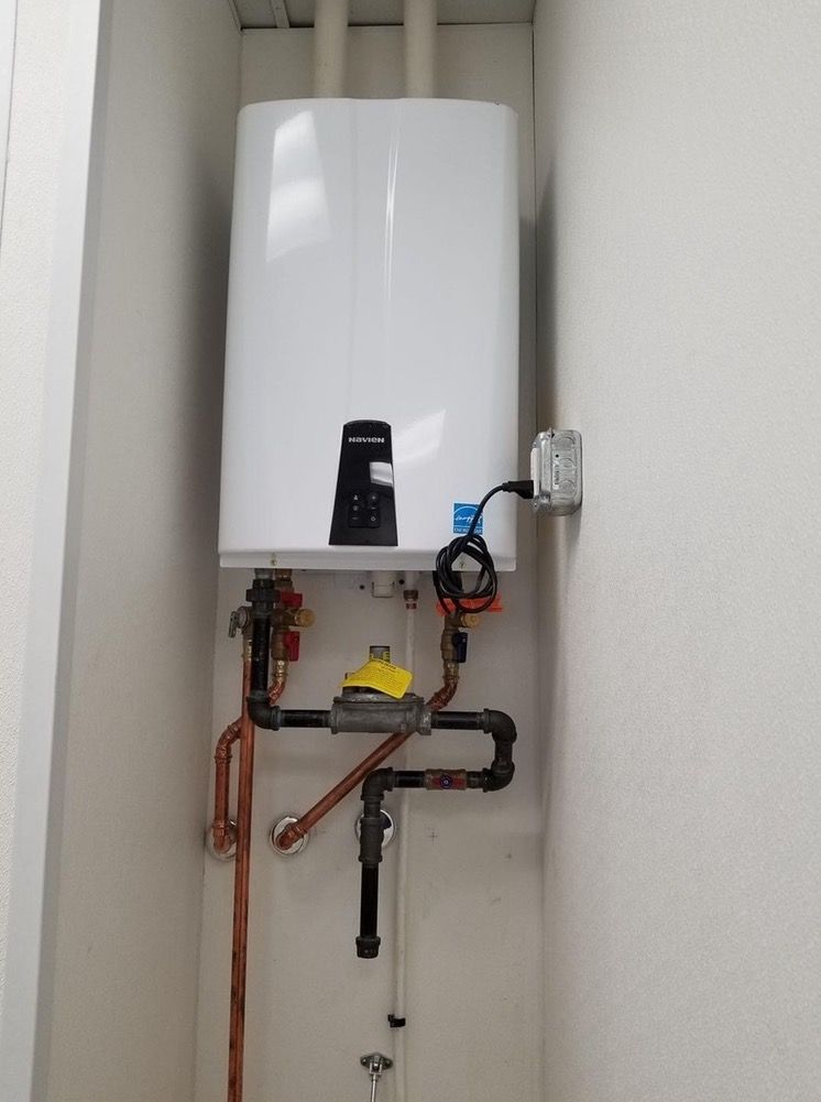 Aqua Plumbing Pros | A white water heater is hanging on a wall next to copper pipes.