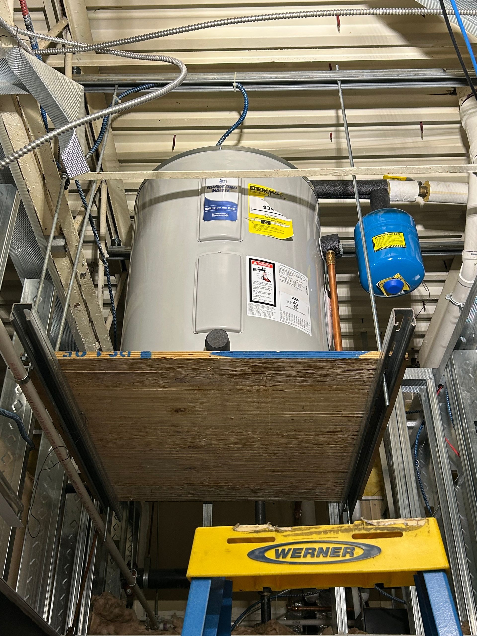Aqua Plumbing Pros | A large water heater is sitting on top of a wooden platform.
